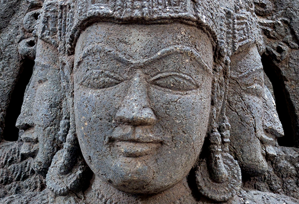 A stone sculpture of a three-headed goddess in which her eyes are closed for meditation.