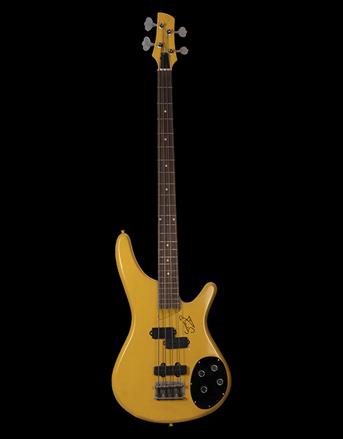 A guitar with a mustard yellow body contains an autograph of Sting on the lower right side.